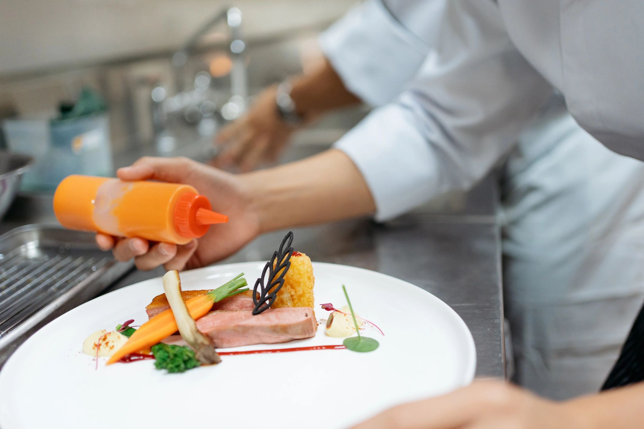 Young chef finishing a gourmet dish with final touches