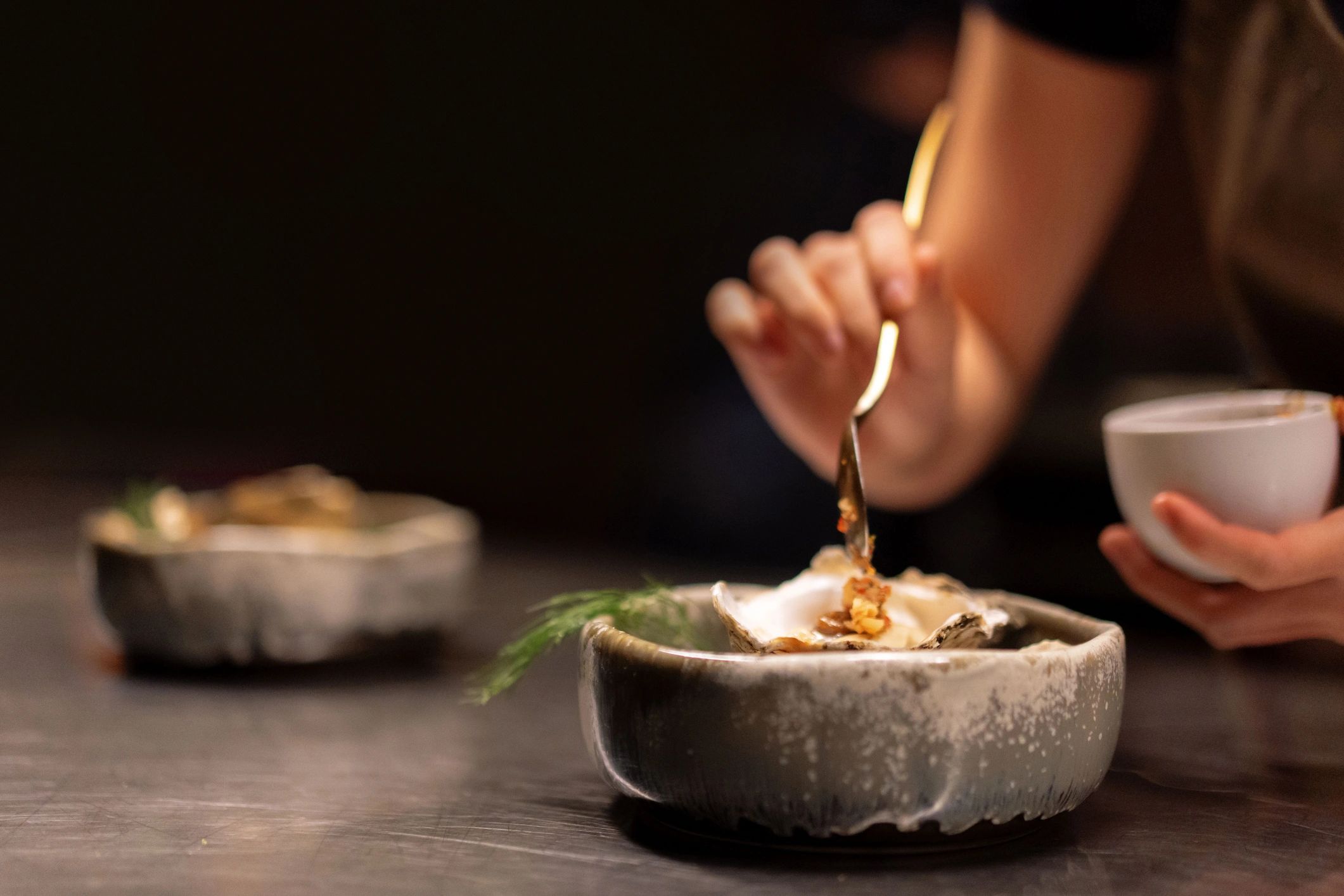 Chef plating and garnishing an oyster dish close up